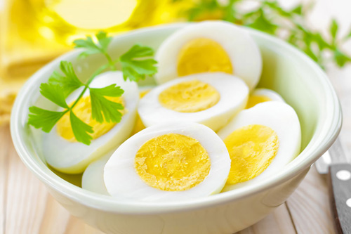 Luộc trứng chín, bóc vỏ và cắt đôi quả trứng theo chiều dọc