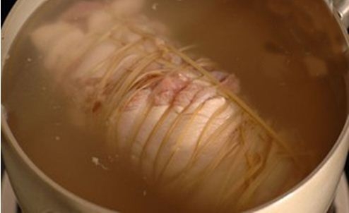 Thịt chân giò dùng lạt buộc thật chặt, cho vào nồi đun trên bếp lửa vừa