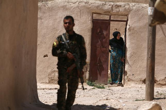 Một thành viên của SDF đứng gần một phụ nữ ở TP Manbij