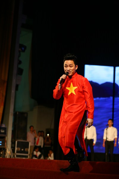 Ca sĩ Tùng Dương trong trang phục áo dài in hình cơ tổ quốc.