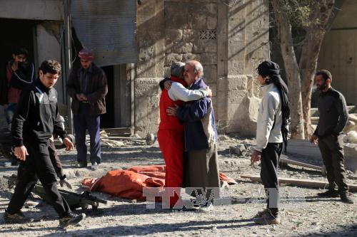 Chiến sự Syria: Nhân viên dân sự Syria an ủi một thân nhân nạn nhân vụ không kích và nã pháo tại Aleppo ngày 19/11. Ảnh: AFP/TTXVN 