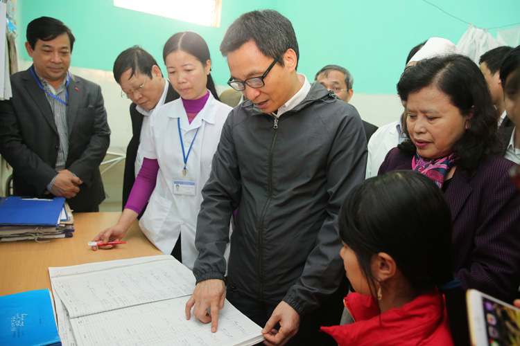  Phó Thủ tướng xem một sổ ghi chép các trường hợp đến khám tại trạm y tế xã Minh Đức. Ảnh: VGP