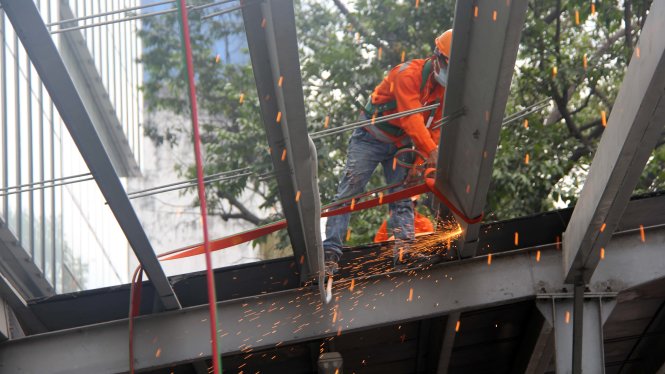 Công nhân dùng đèn khò gió đá để cắt khung sắt, mái che - công trình vi phạm của tòa nhà SaiGon Center. Ảnh: Tuổi trẻ 