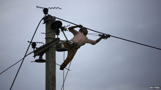  Một người công nhân điện lực đang làm việc trên một trụ điện ở thủ đô Kathmandu. Ảnh: Reuters