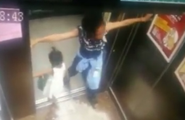 Người mẹ vì mải sử dụng điện thoại mà để con kẹt tay ở cửa thang máy. Ảnh cắt từ clip.