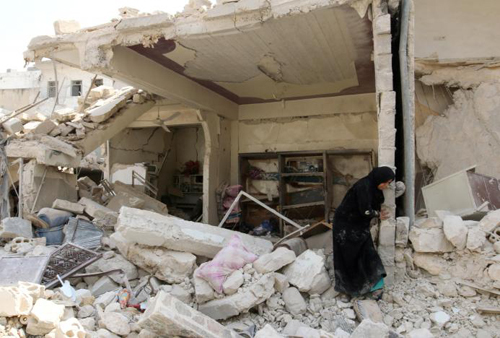 Tình hình chiến sự Syria mới nhất: Một phụ nữ đứng giữa đống đổ nát sau một cuộc không kích vào vùng Bab al-Nairab do phiến quân kiểm soát ở thành phố Aleppo, Syria