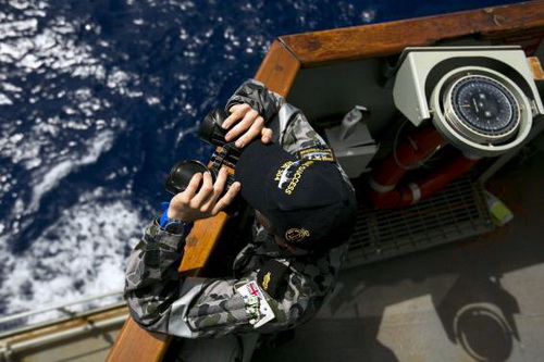 Một lính hải quân Úc đang đứng trên tàu HMAS Success, dùng ống nhòm lùng tìm tung tích chiếc máy bay mất tích - Ảnh: Reuters