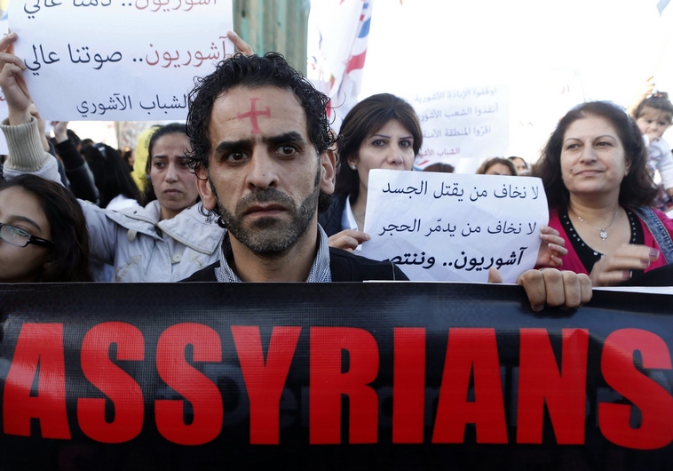 Những người Assyrian cầm biểu ngữ khi họ diễu hành vì những người bị nhóm khủng bố IS bắt giữ