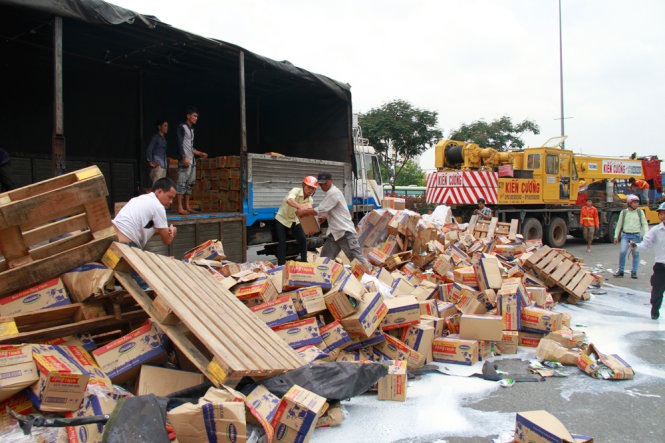 Người dân giúp tài xế vụ lật xe container chở sữa Vinamilk gom các thùng sữa bị đổ