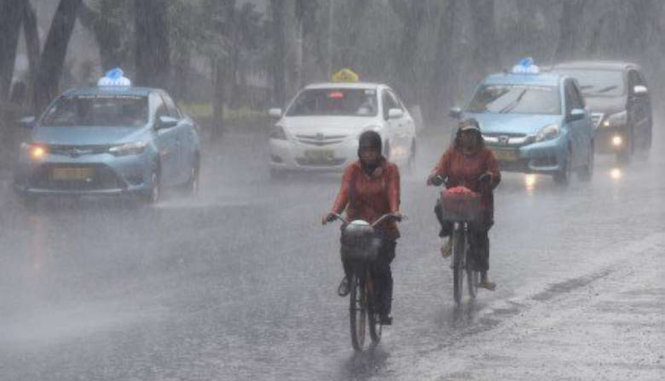 Hai phụ nữ đạp xe trong cơn mưa lớn tại tỉnh miền Trung Java. Ảnh: JAKARTA POST