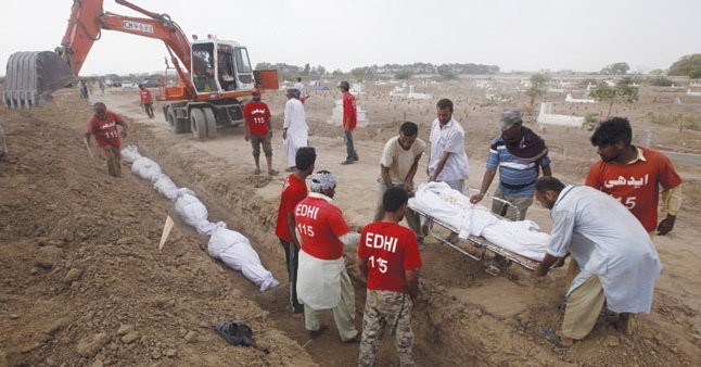 Pakistan dùng máy xúc để đào mộ tập thể, chôn cất những người thiệt mạng vì đợt nóng trong tháng 6. Ảnh Reuters