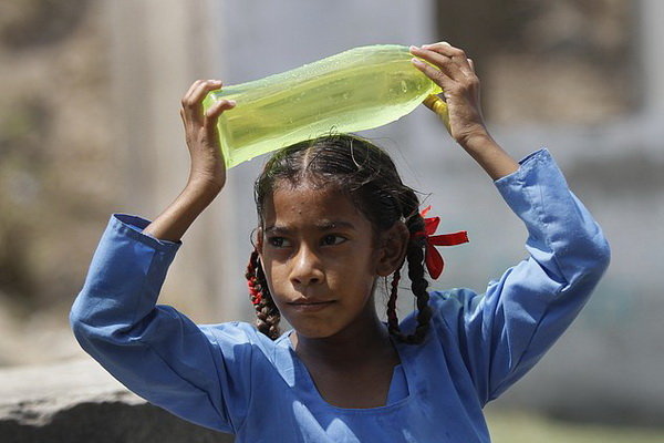 Một học sinh Ấn Độ đội chai nước lên đầu để xoa dịu cái nắng nóng kỷ lục