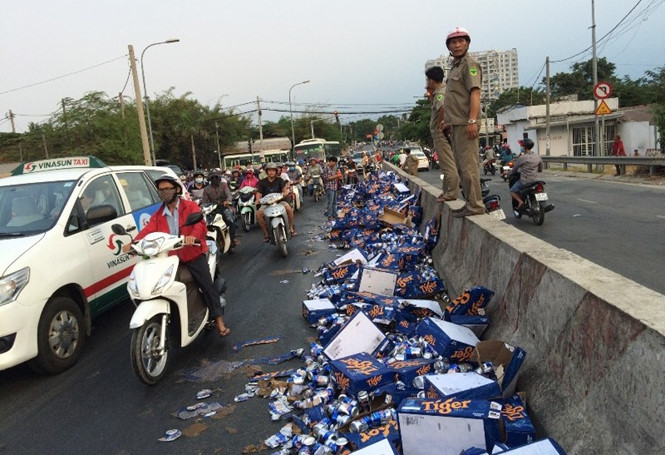 Người dân giúp tài xế gom hàng trăm thùng bia bị đổ xuống đường
