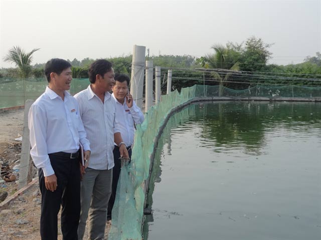 Nguyễn Văn Thêm (giữa) đang đưa khách đi tham quan các ao cá. Ảnh: Nông nghiệp Việt Nam