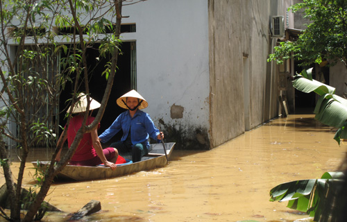 Hai phụ nữ trong  vùng lũ ở Thanh Hóa phải dùng thuyền di chuyển vào nhà vì các con đường bộ đều bị ngập sâu