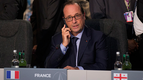 Tổng thống Pháp Francois Hollande nghe điện thoại tại một hội nghị của NATO năm ngoái