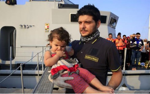 Cảnh sát biển Italia bế một em bé tỵ nạn người Syria cập bãi biển Hy Lạp ngày 10/8 