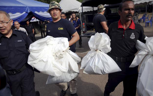 Nhân viên pháp y Malaysia mang những chiếc bao đựng thi thể sau khi cảnh sát nước này tìm thấy hàng trăm ngôi mộ tập thể 