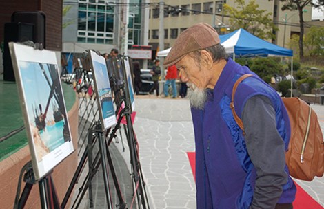 Người dân Hàn Quốc xem các bức ảnh tại triển lãm về đảo nhân tạo trái phép trên Biển Đông