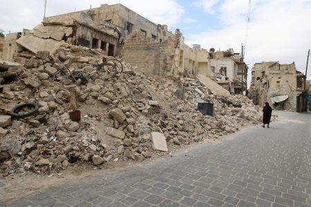 Một phụ nữ đi ngang những tòa nhà đổ nát ở Aleppo, theo tình hình chiến sự Syria mới nhất