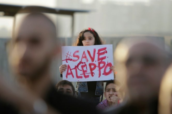 Một bé gái Syria cầm tấm biển ghi Hãy cứu Aleppo trong một cuộc tuần hành biểu thị tinh thần đoàn kết với người dân Aleppo