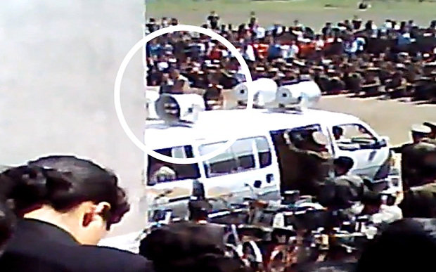 Hai người đàn ông Triều Tiên (khoanh tròn) bị đem ra xét xử công khai trước đám đông dân chúng