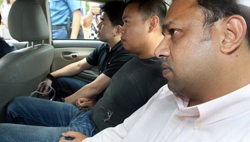 Iskandar Rahmat (giữa) ngồi trong xe với sự canh chừng nghiêm ngặt của hai nhân viên cảnh sát - Ảnh: therealsingapore.com